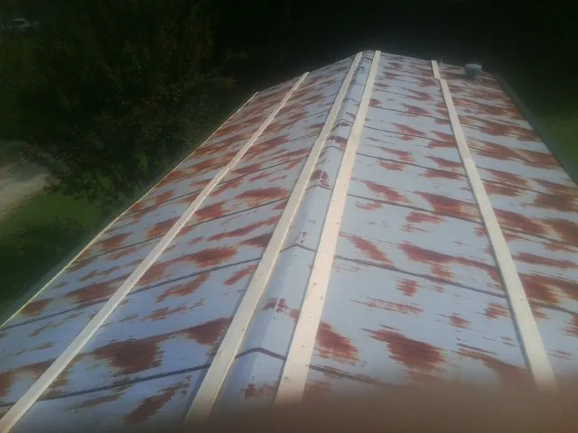 Rusted metal roof panels with new wood purlins before replacement — Storm Damage Roof Repair in Maplewood by Roofing Brothers
